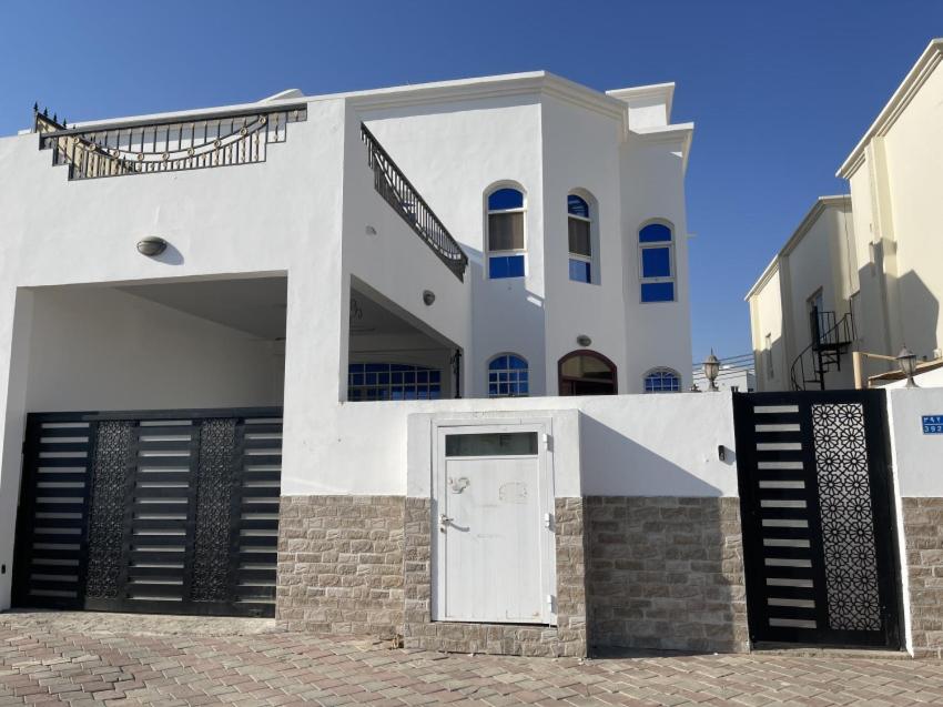 a white building with a white door and a staircase at Hostel Maral in Mawāliḩ