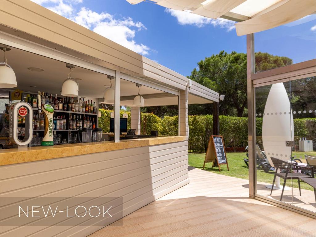 a bar on a patio with a surfboard behind it at Aqua Pedra Dos Bicos Design Beach Hotel - Adults Friendly in Albufeira