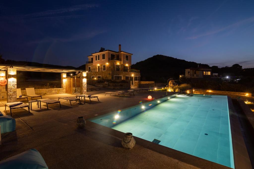 a swimming pool at night with a house in the background at Lampetos Houses Molyvos in Mythimna