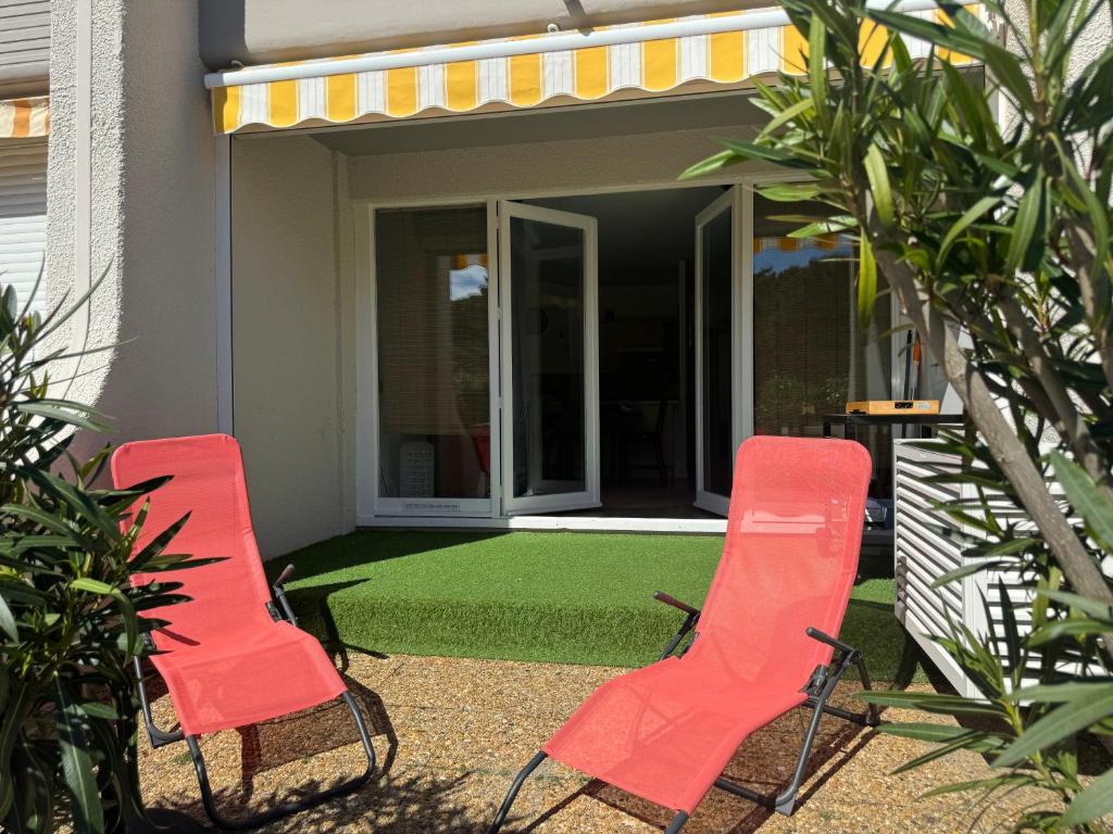 deux chaises rouges assises devant une maison dans l'établissement Le Marin, à Saint-Cyprien