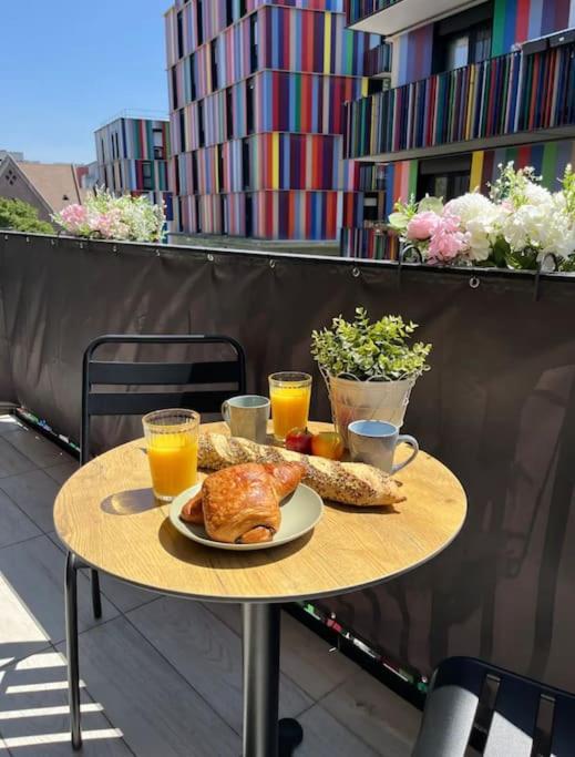 a table with a plate of food and two glasses of orange juice at Charmant appartement avec balcon proche de Paris in La Courneuve