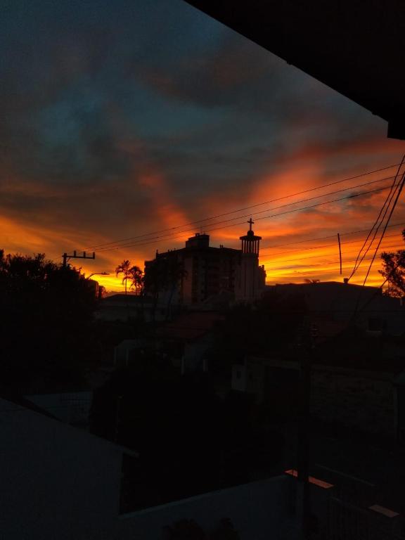 a sunset with a building in the background at Quarto acolhedor no Balneario in Florianópolis