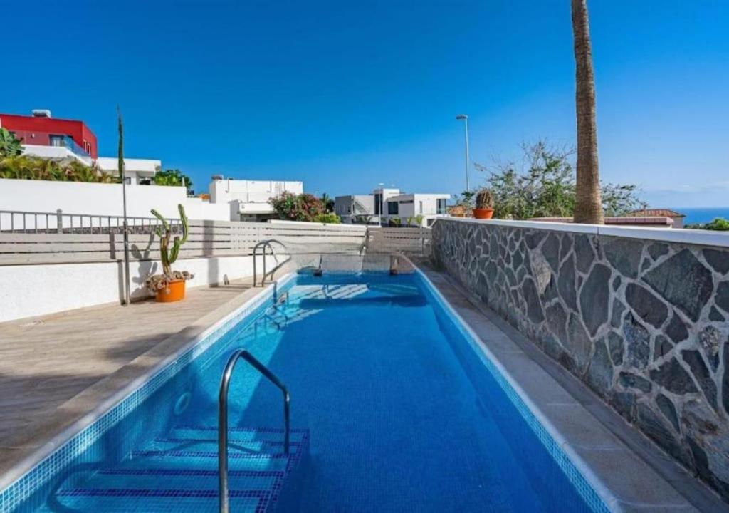 a swimming pool with blue water next to a wall at Tranquil 2BR :Private Pool & Ocean Views in Callao Salvaje
