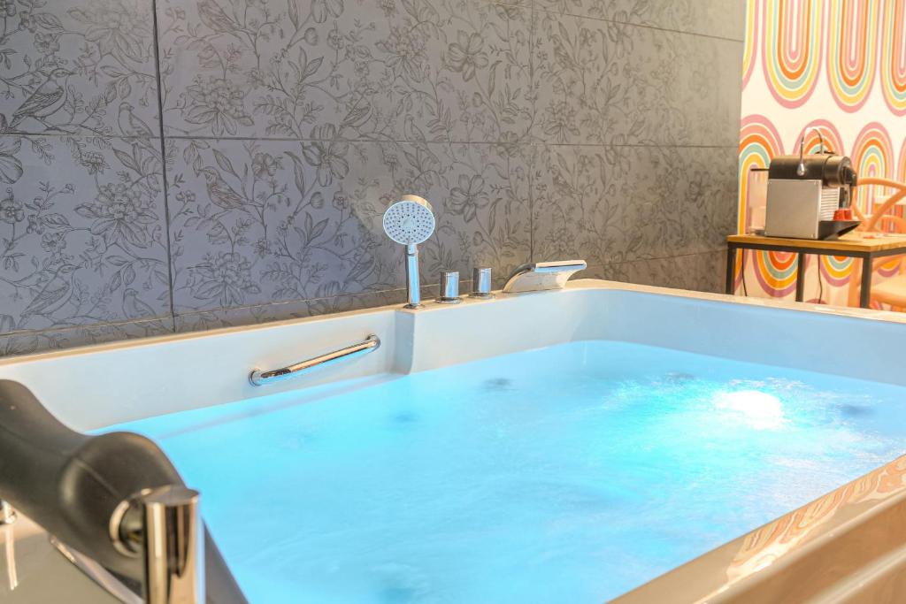 a blue tub in a bathroom with a sink at Design et Pop avec balnéo in Lyon