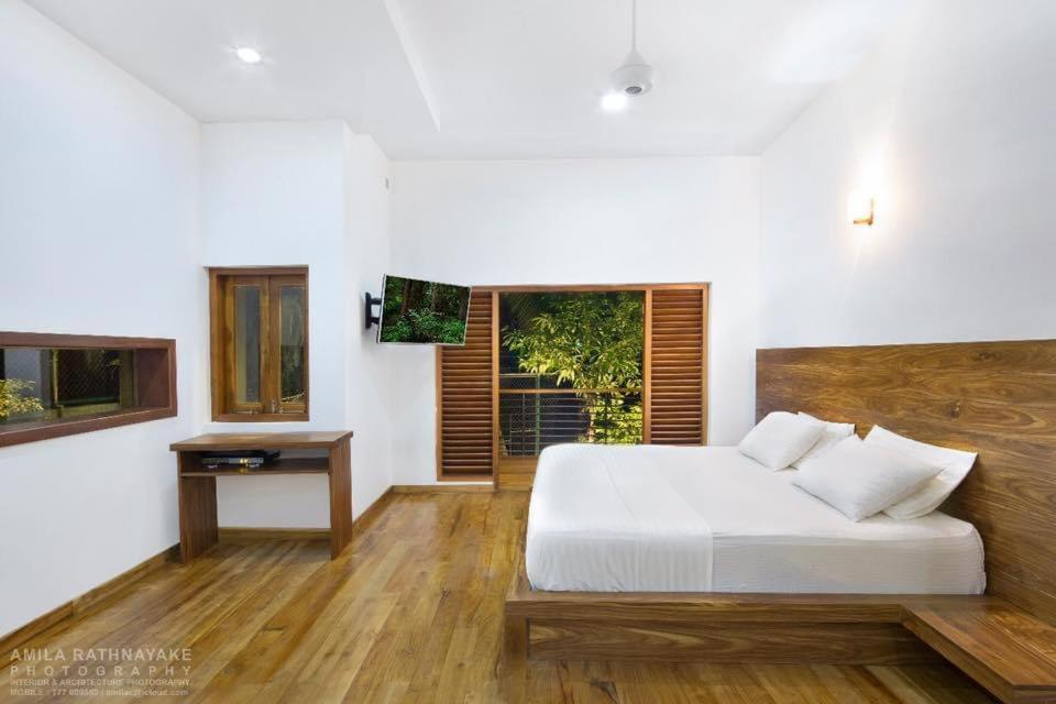 a bedroom with a white bed and a table at Villa 47 Colombo in Pannipitiya