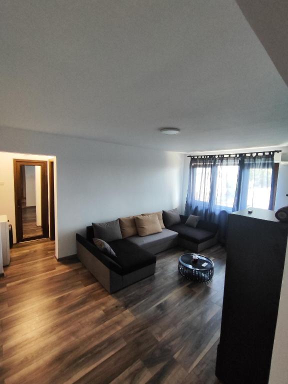 a living room with a black couch and wooden floors at Apartament Luna in Jurilovca