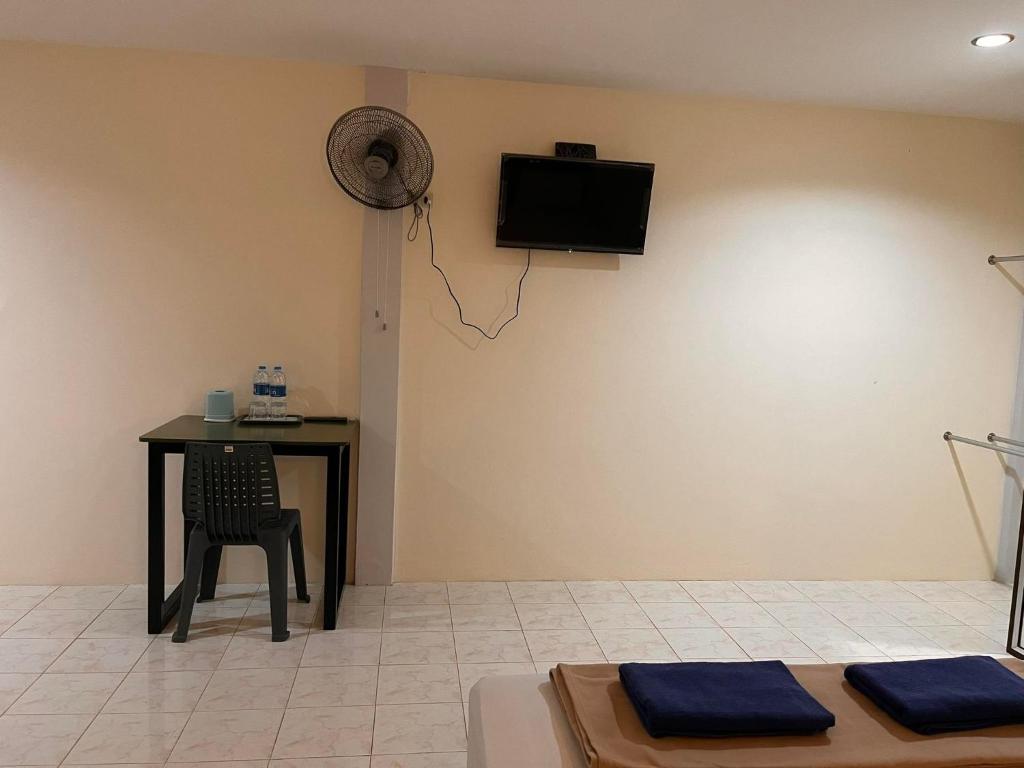 Habitación con mesa y TV en la pared. en โรงแรมเมโทร2 Metro2, en Satun
