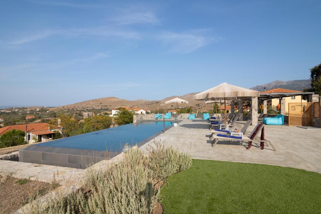 a swimming pool with blue lounge chairs at Lampetos Houses Molyvos in Mythimna