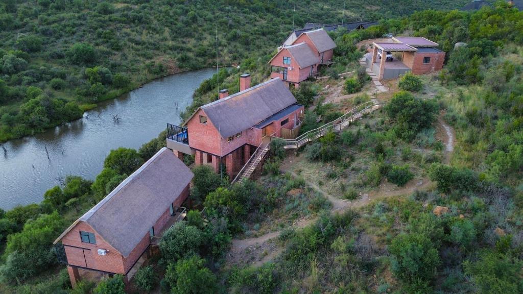 a group of houses on a hill next to a river at Cliffhanger Lodge in Mabula