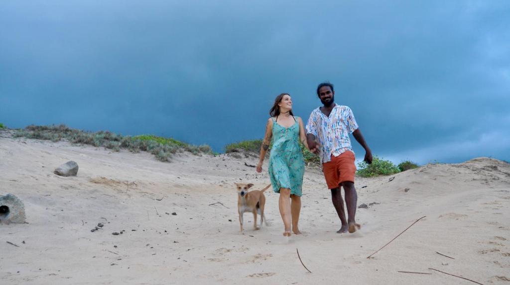 a man and a woman walking a dog on the beach at Back of Beyond Dune Camp Yala in Yala
