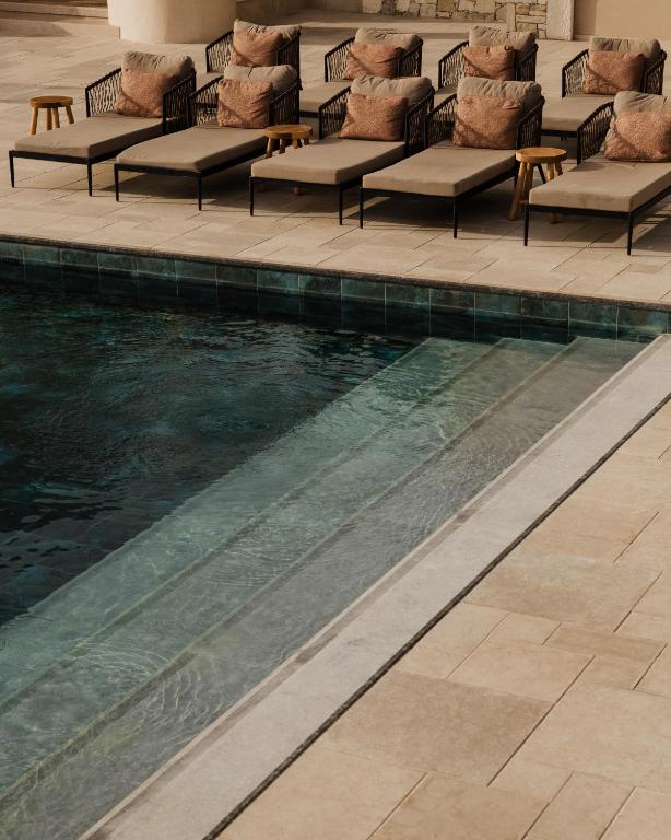 una piscina con tumbonas y sillas junto a una piscina en Momi Slow Living Hotel, en Hersonissos