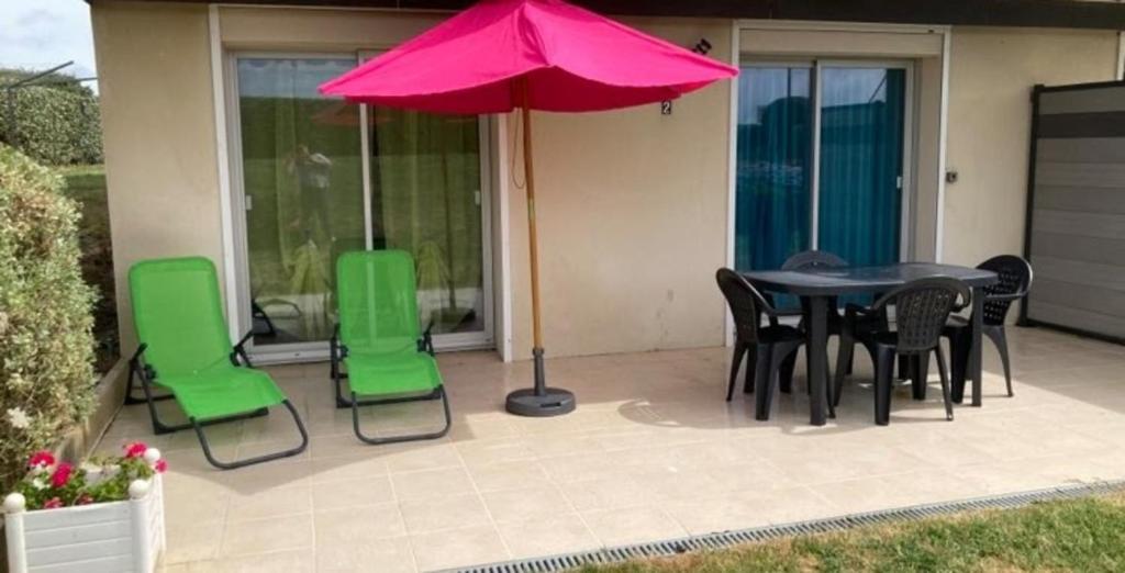 un patio avec une table, des chaises et un parasol dans l'établissement Cozy cocoon just a stone's throw from the sea, au Pouliguen