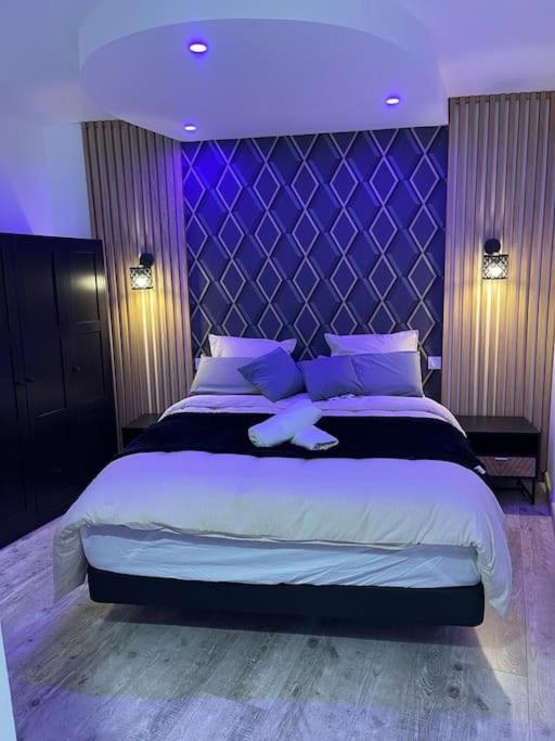 une chambre avec un grand lit avec un éclairage violet dans l'établissement appartement design limite Paris métro 13et14 JO 2024, à Saint-Ouen