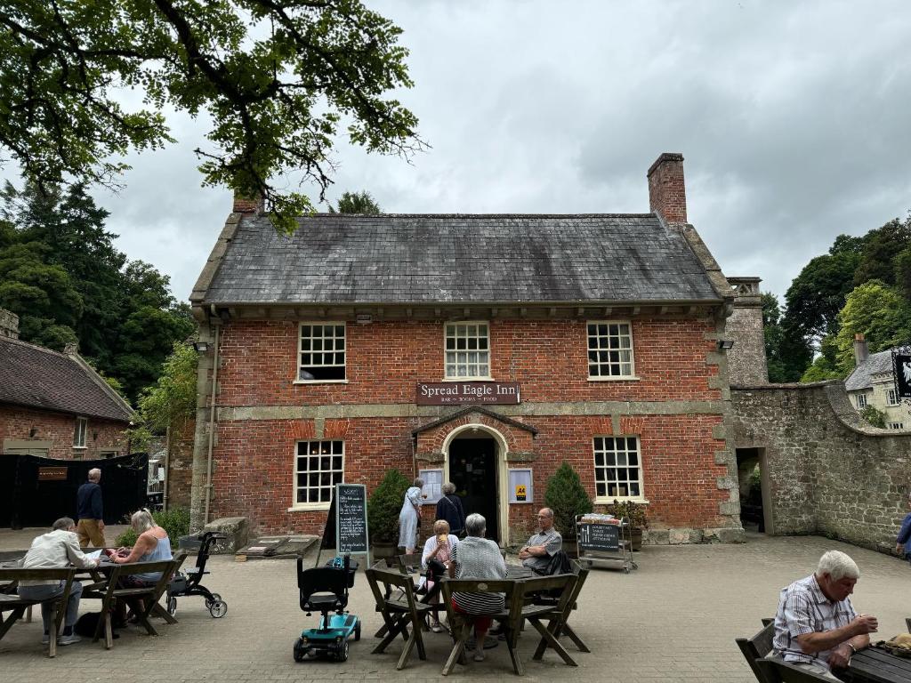 a group of people sitting at tables in front of a brick building at Spread Eagle Inn in Stourton