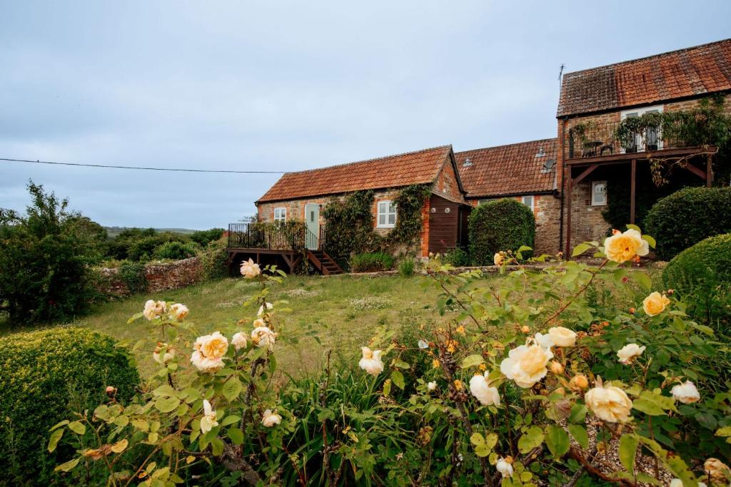 ein Haus mit Blumen vor einem Hof in der Unterkunft Pigsty Cottage - Rudge Farm Cottages in Bridport
