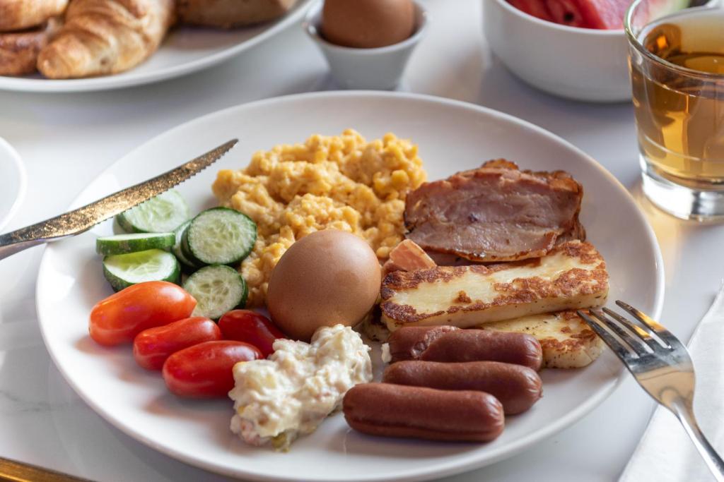 a plate of food with sausage eggs and vegetables at Rise Urban Art Hotel in Larnaca