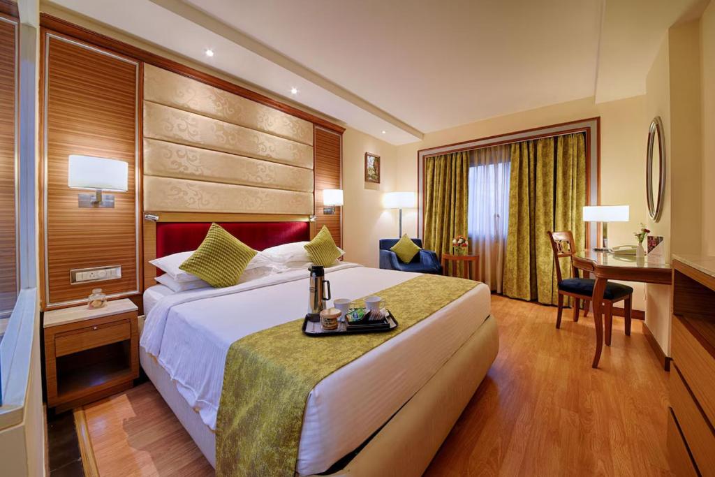 een hotelkamer met een groot bed en een bureau bij De Sovrani in kolkata