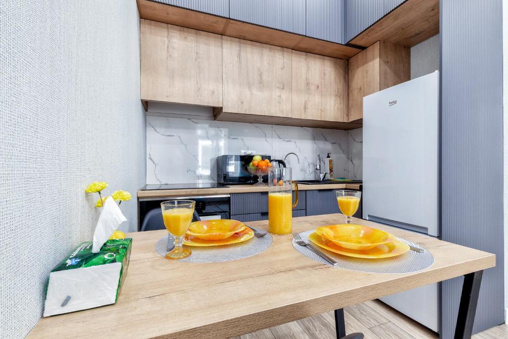 a kitchen with a wooden table with plates of food on it at "Бирюзовый оазис" Премиум квартира на Туран - Улы Дала рядом с Легкоатлетическим комплексом in Astana