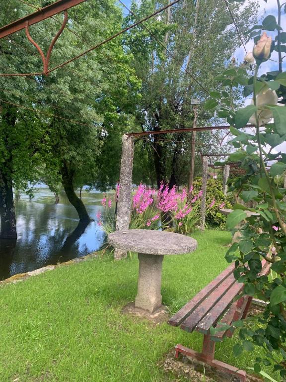 a stone bench sitting in the grass next to a river at Casa das Fontes in Ponte da Barca