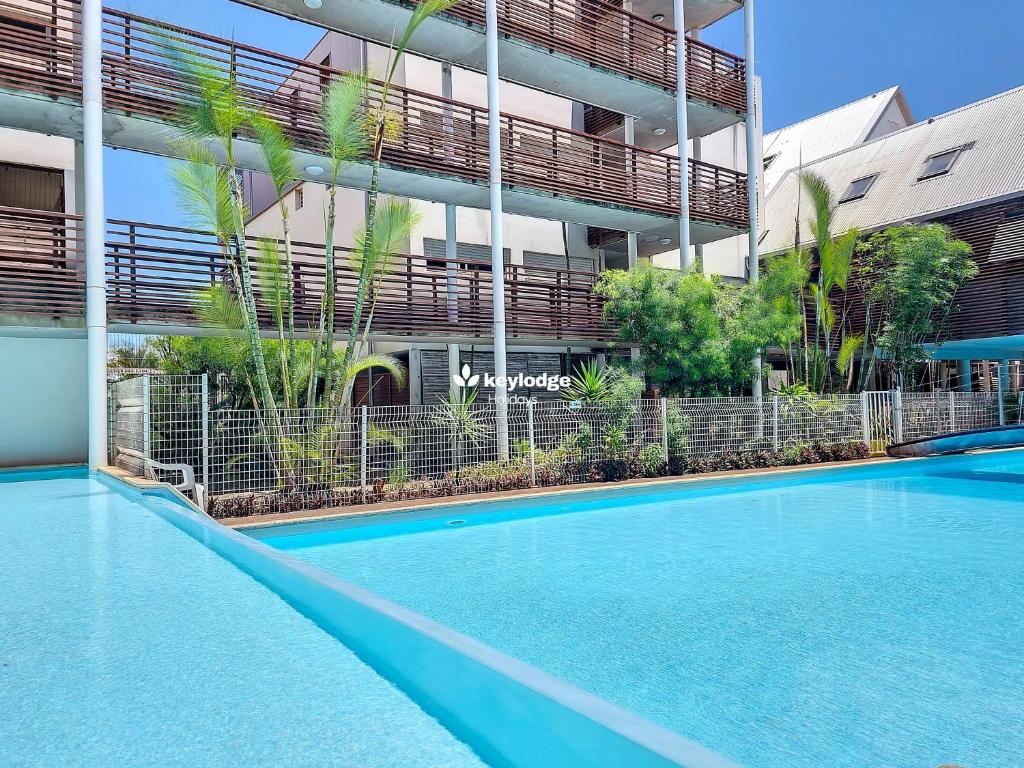 a swimming pool in front of a building at Douceur Exotique - 2 chambres - piscine partagée - centre-ville de Saint-Pierre in Saint-Pierre