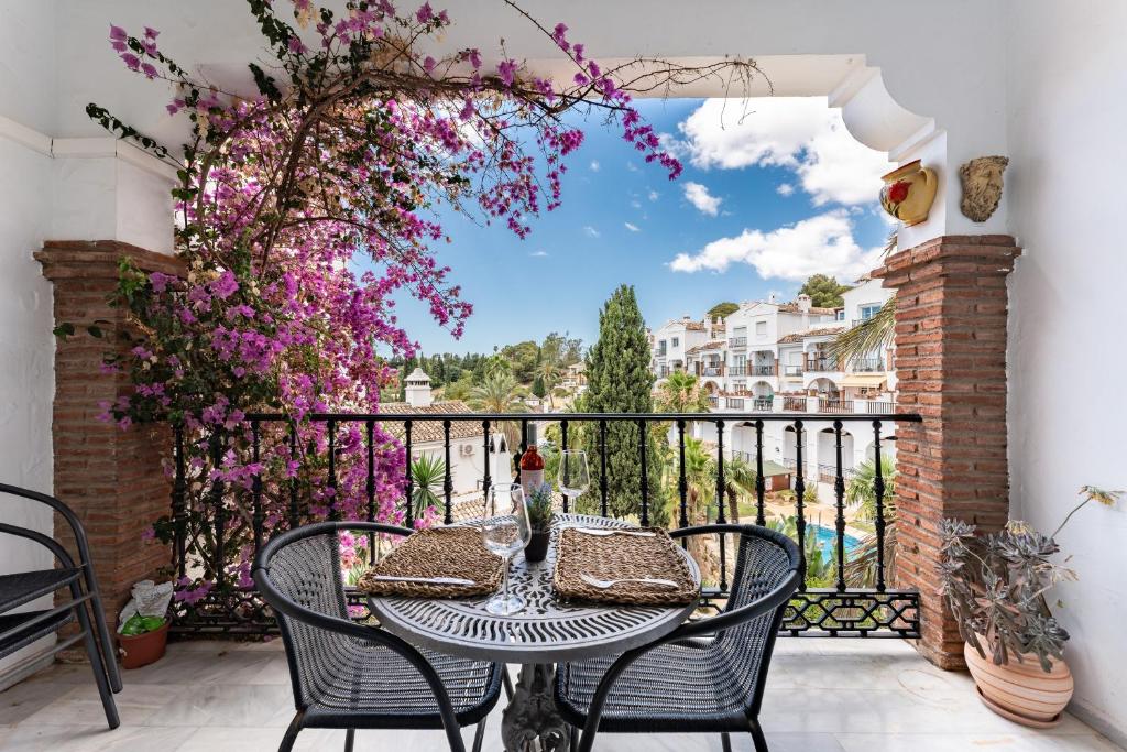 a table and chairs on a balcony with flowers at Lovely apartment in peaceful area in Mijas