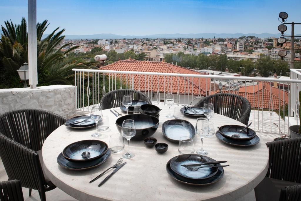 a table with plates and wine glasses on a balcony at PositiveSpace Kalamata Heights in Kalamata