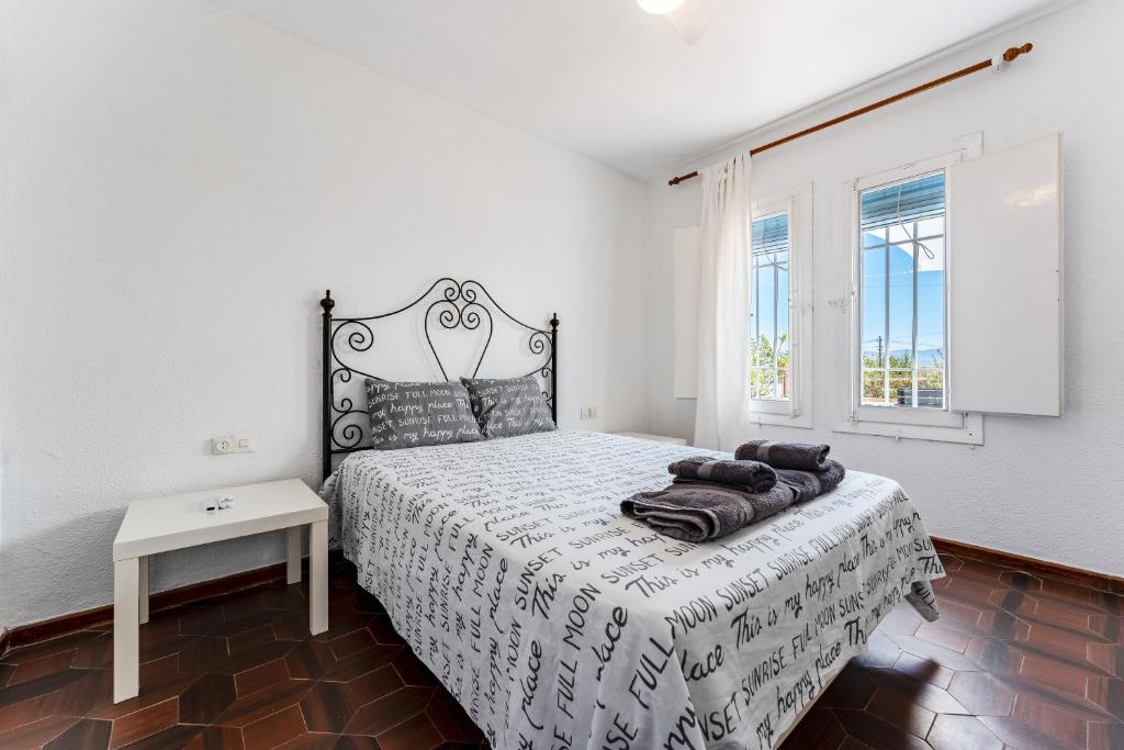 Schlafzimmer mit einem Bett mit einer schwarzen und weißen Tagesdecke in der Unterkunft Villa Namaste in Alhaurín de la Torre
