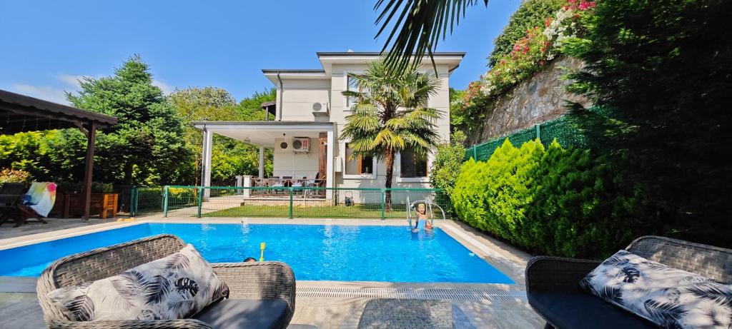 a pool with two chairs and a person in the water at family villas sapanca in Sapanca
