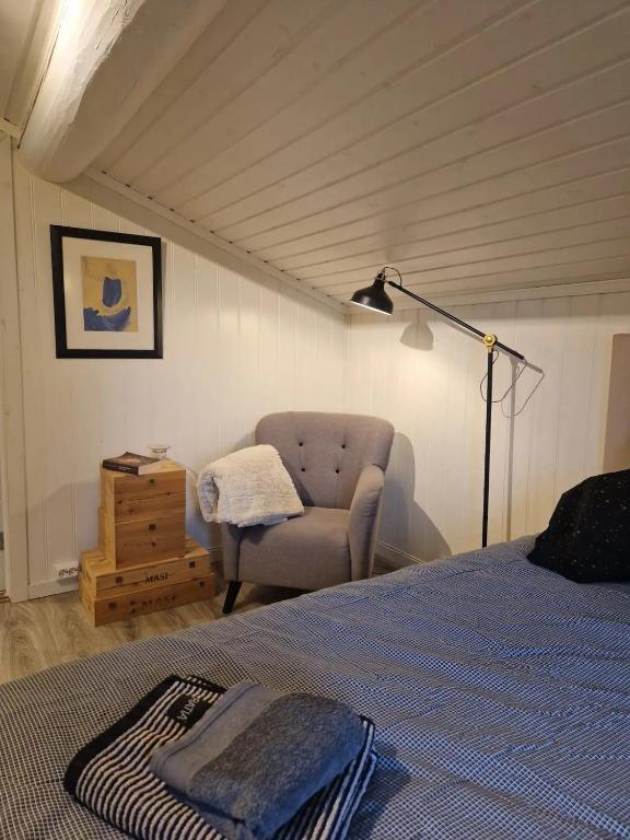 a bedroom with a bed and a chair and a lamp at Koia Guesthouse in Flesberg