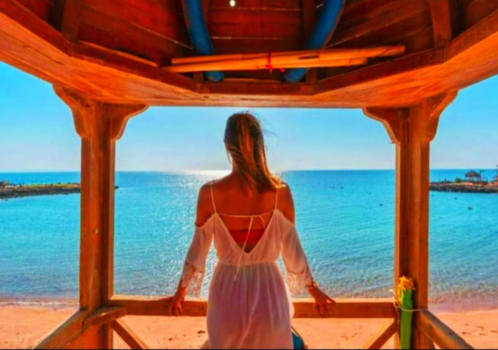 Una mujer con un vestido blanco mirando hacia el océano en Davinci Beach Resort, en Hurghada