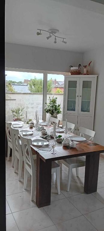a dining room table with white chairs and a large table with glasses at Enjoy in Wenduine