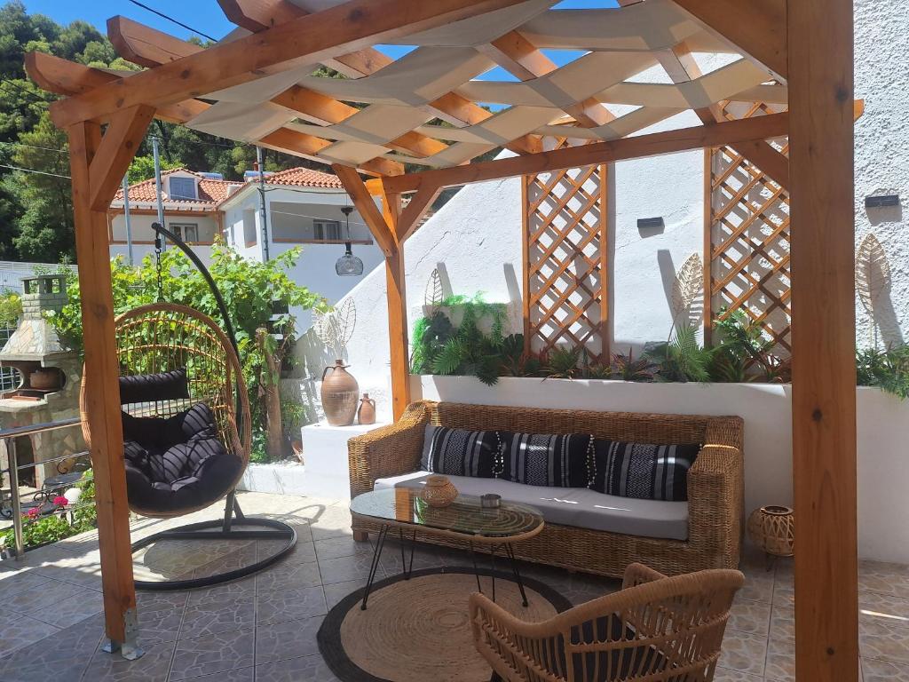 a wooden pergola with chairs and a table on a patio at Vithos in Agnontas