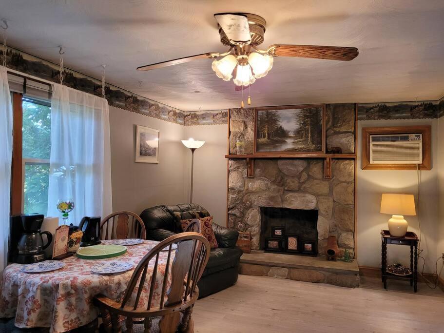 een woonkamer met een tafel en een stenen open haard bij Lake Congamond Suffield House in Granby