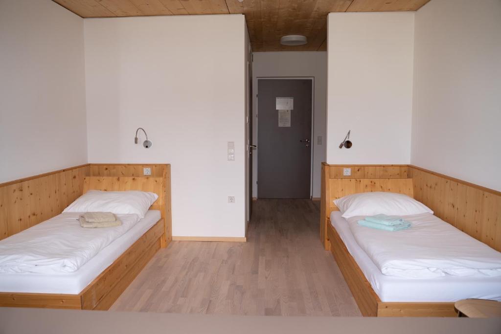 2 letti in una camera con pareti bianche e pavimenti in legno di Waldcampus Österreich a Traunkirchen