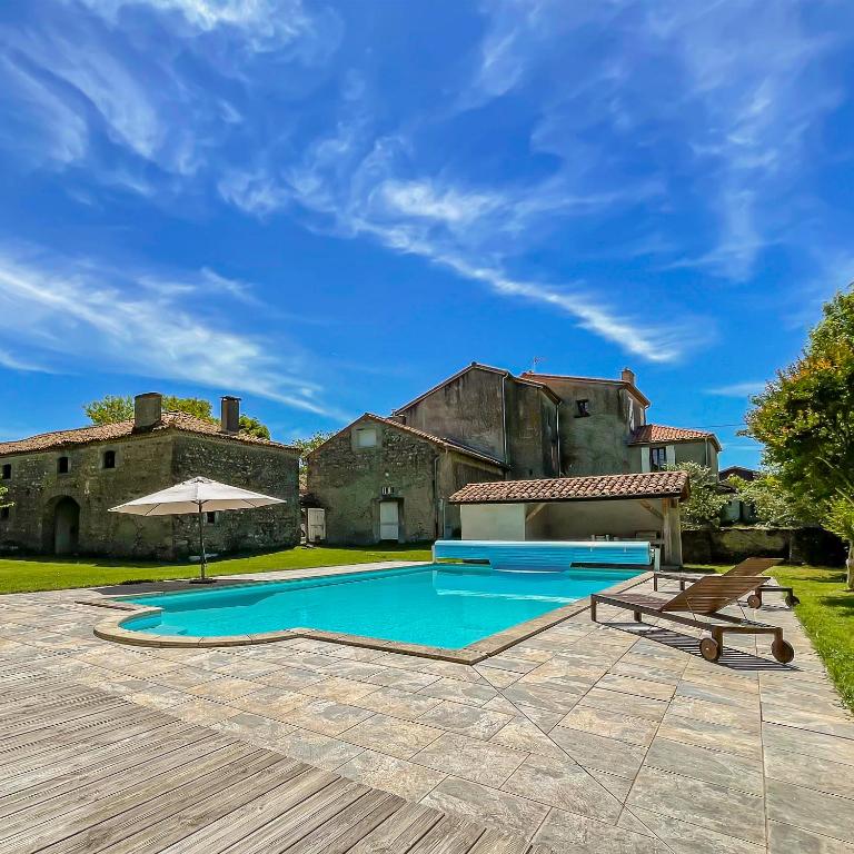 an outdoor swimming pool in front of a house at Retraite Royale à Valentine in Valentine