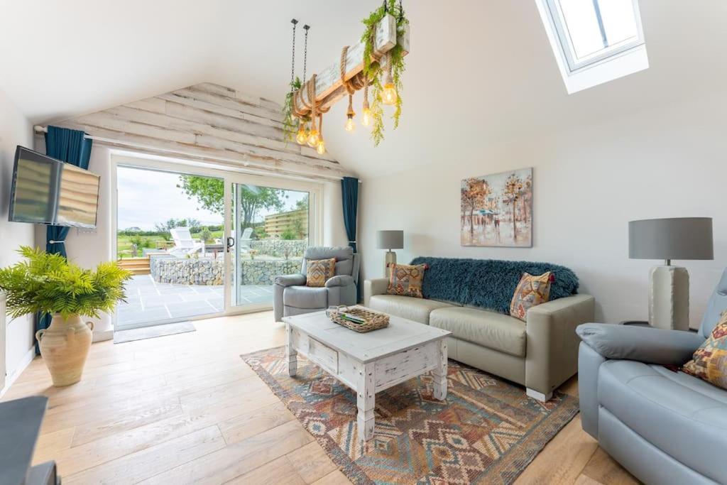 ein Wohnzimmer mit Sofa und Tisch in der Unterkunft The Cow Stalls - Stunning Farmhouse with Wonderful Views and Garden - Close to Corfe Castle in Langton Matravers