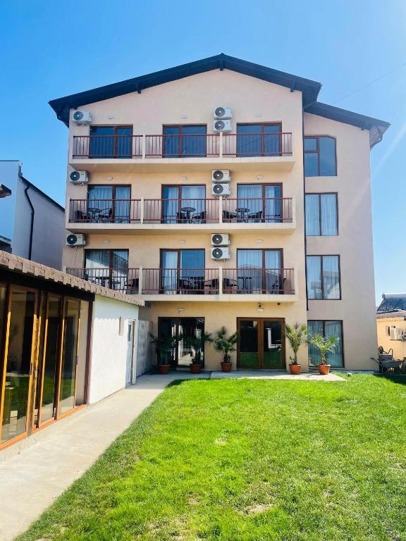 an apartment building with a lawn in front of it at Pensiunea Riviera in Costinesti