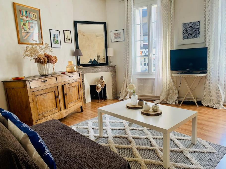 - un salon avec une table basse blanche et une télévision dans l'établissement Maison de ville au Cœur d'Angoulême- 2 chambres-Wifi- Cosy - Idéal de 1 à 6 Personnes - conciergerie J&N, à Angoulême