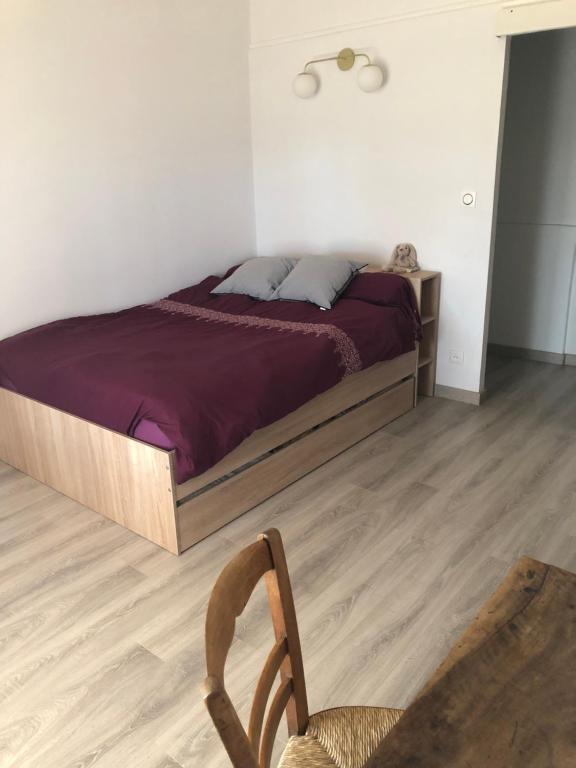 - une chambre avec un lit et un fauteuil en bois dans l'établissement La Respelido studio ds maison campagne, à Cabannes