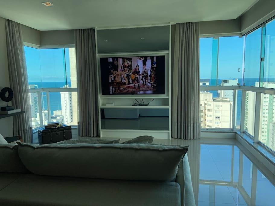 a living room with a couch and a television at Terra Brasilis Linda vista mar, completo, aconchegante, bem localizado in Balneário Camboriú