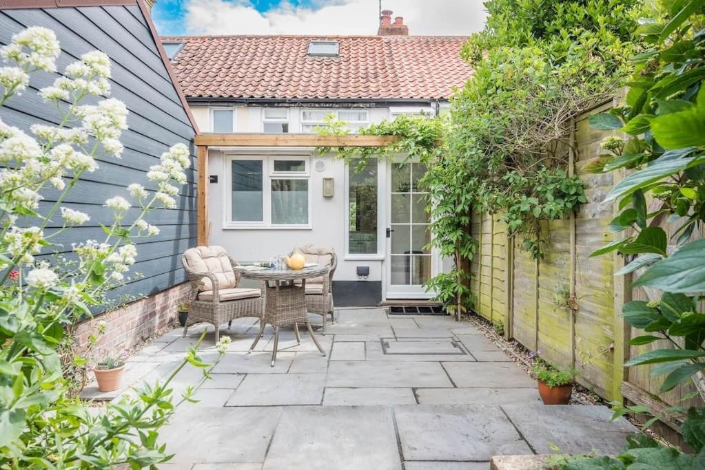 un patio con tavolo e sedie di fronte a una casa di Angel Cottage, Wenhaston a Halesworth