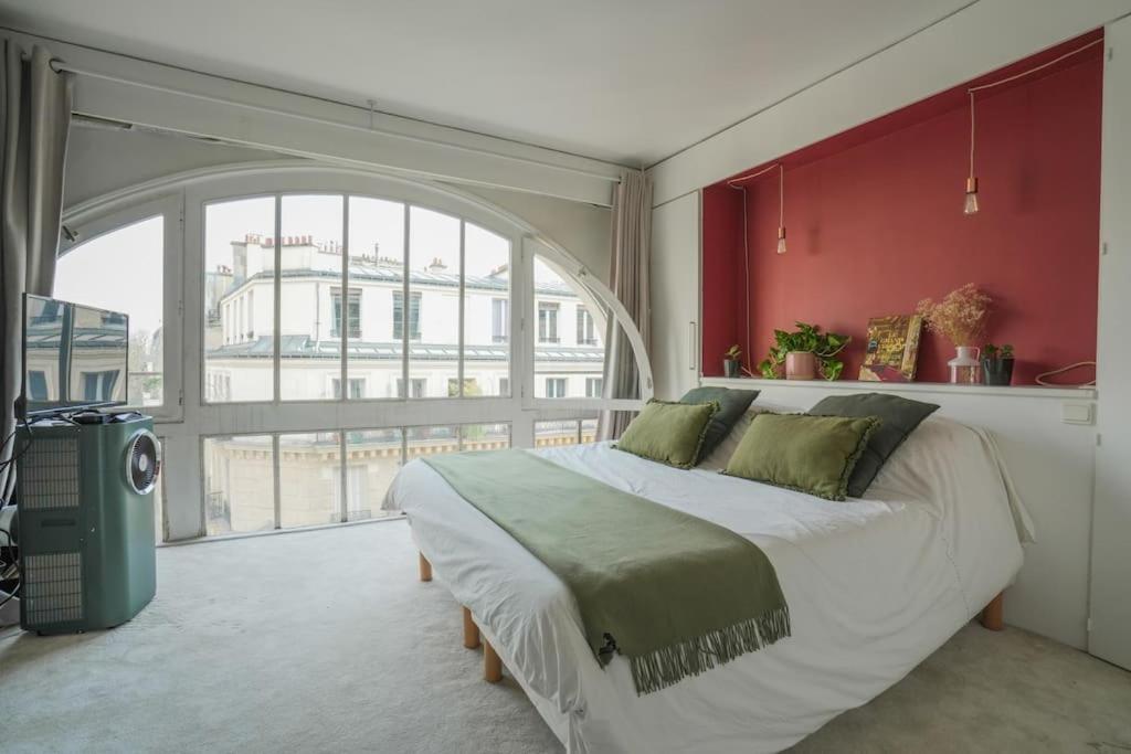 una camera con un grande letto e una grande finestra di Eiffel Tower Vicinity Gem a Parigi