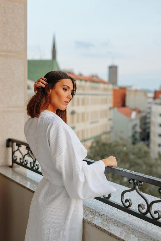 una donna in abito bianco in piedi su un balcone di Hotel Balkan a Belgrado