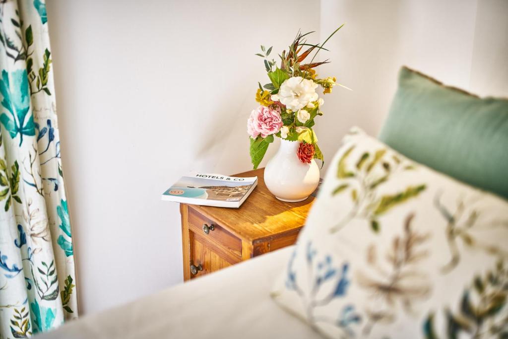 a vase with flowers on a table with a pillow at La Ferme D'Augustin in Saint-Tropez