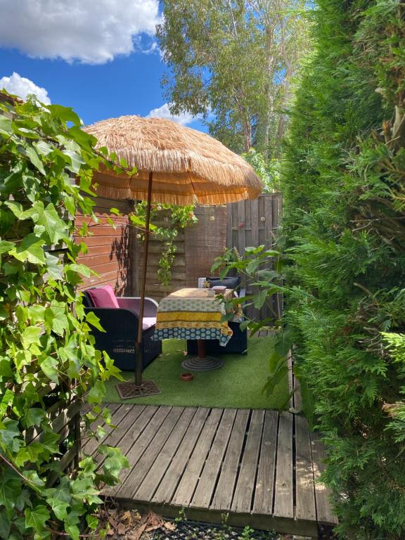 a wooden deck with an umbrella and a table at Studio au calme à la campagne 10mn centre ville in Béziers