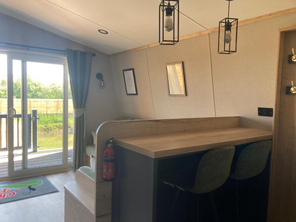 a room with a bar with chairs and a window at Chapel Fields Holiday Park in Chapel Saint Leonards