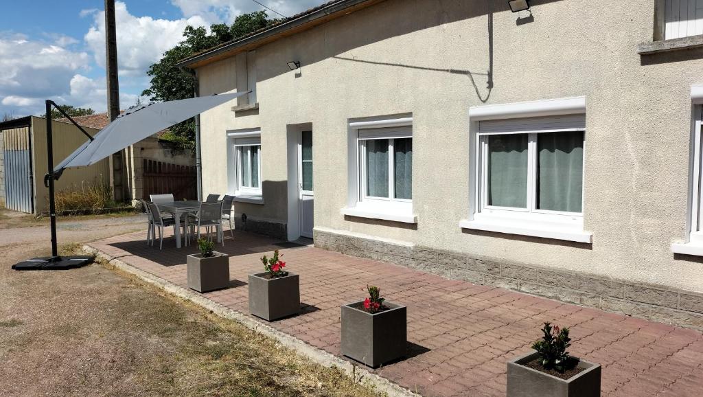 un patio avec une table et des chaises devant un bâtiment dans l'établissement Le p'tit Québécois, à Les-Trois-Moutiers