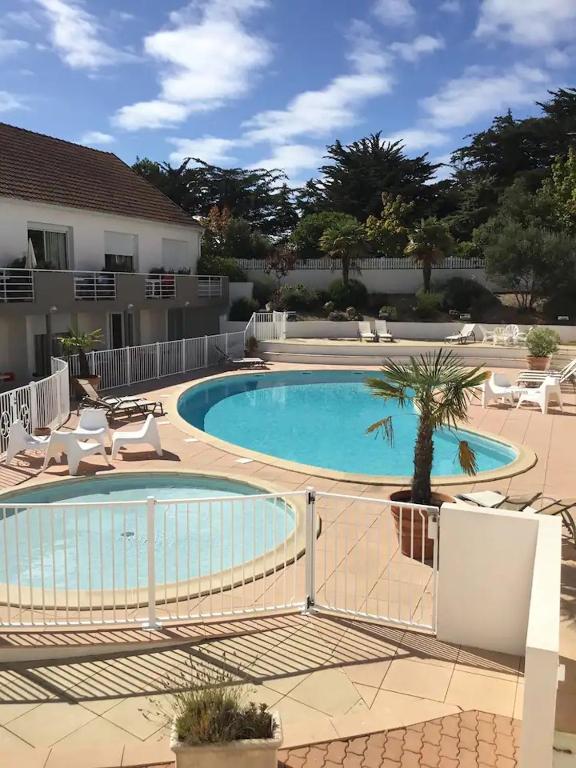- une piscine avec un palmier à côté d'un bâtiment dans l'établissement Résid Azur, à Saint-Jean-de-Monts
