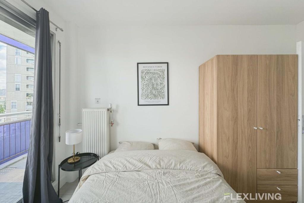 une chambre avec un lit et une armoire en bois dans l'établissement Flexliving - room - Mouchez, à Paris