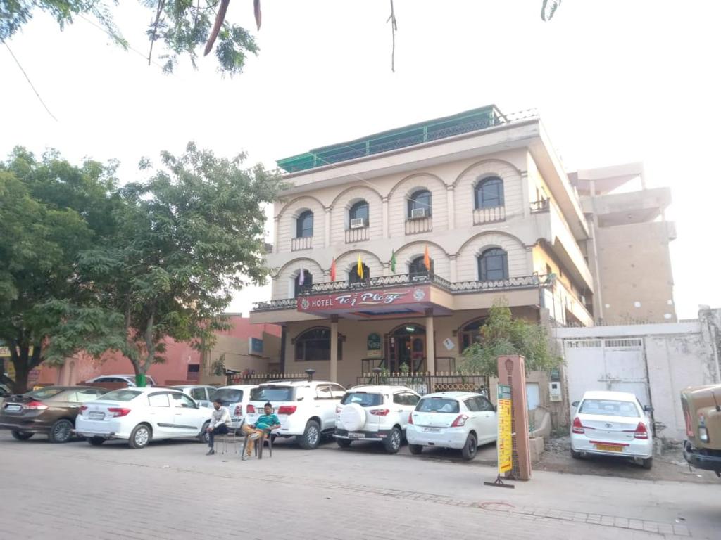 a building with a lot of cars parked in front of it at Hotel Taj Plaza, VIP Road, Agra in Agra